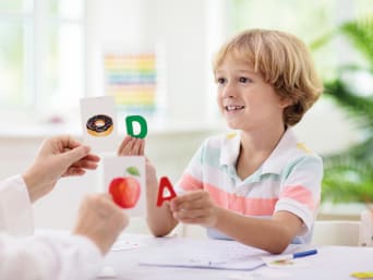Tecniche di apprendimento per bambini: bambino assegna le lettere al cibo corrispondente.