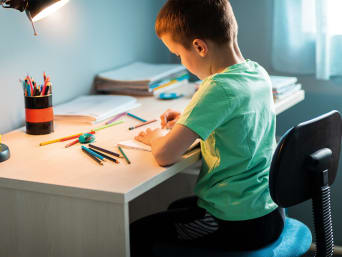 Un garçon fait ses devoirs sur son bureau.