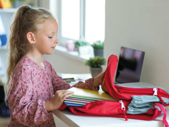 Cómo organizar el material escolar: una niña prepara la mochila del colegio.