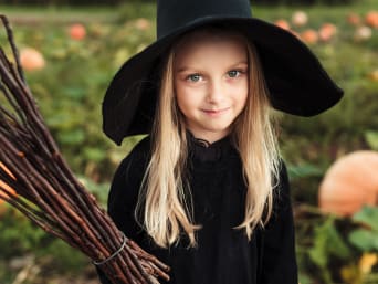 Hexen-Kostüm für Kinder selber machen: Mädchen in einem schwarzen Hexen-Kostüm.