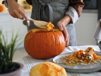 Pasos para tallar una calabaza: una mujer retira las semillas y la pulpa de una calabaza de Halloween.