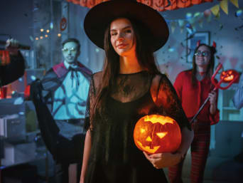 Eenvoudige halloweenkostuums om zelf te maken: vrouw in een heksenkostuum op een feestje.