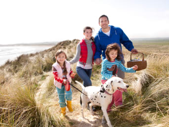 Tierbetreuung – Familie macht Urlaub am Strand mit ihrem Hund.