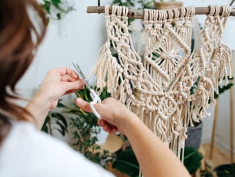 Macramé for beginners: a woman knotting a wall hanging with macramé cord.
