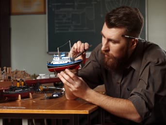 Modellbau – Mann arbeitet an seinem Modellschiff.