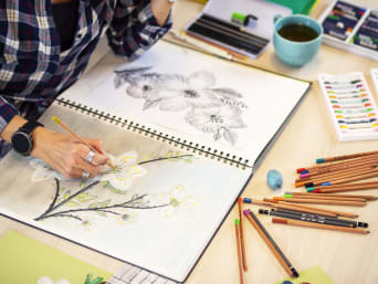 Une femme dessine des fleurs dans des perspectives et couleurs différentes.