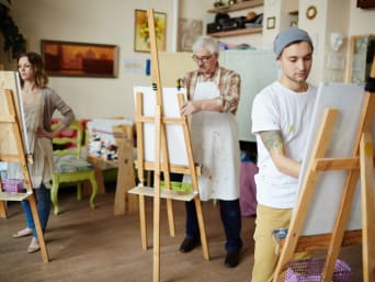 Malen lernen für Erwachsene: Teilnehmer eines Kunstkurses konzentrieren sich auf ihre Staffeleien. 