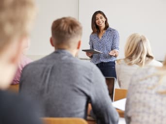 Mehrsprachigkeit Vorteile: Eine Lehrerin unterrichtet eine Gruppe Erwachsener. 