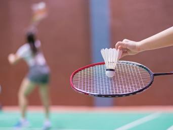 Badminton Training für Kinder: Detailaufnahme von einem Badmintonschläger und einem Federball.