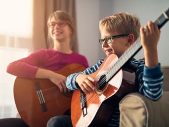 Clases de guitarra para niños: un niño aprende a tocar la guitarra en clase.