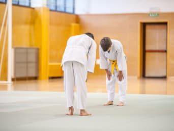 Aprender artes marciales: dos pequeños judocas con judogi se saludan.