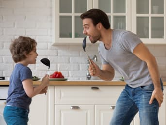 Śpiewanie z dziećmi – tata z synem śpiewają razem w kuchni.