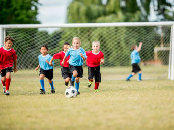 Zainteresowania dzieci – grupa maluchów gra w piłkę nożną.