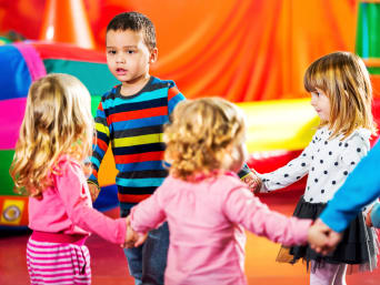 Des jeunes enfants danse en rond ensemble.