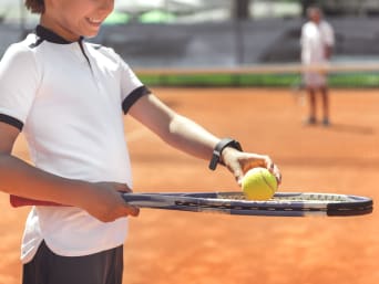 Tennis für Kinder – Kind mit Schläger und Ball beim Tennistraining.