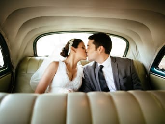 Costumbres de boda: una pareja de novios se besa en el coche nupcial.