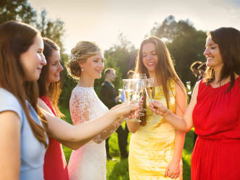Women’s wedding guest dresses: a group of women toasting with the bride.