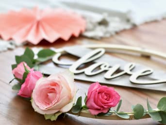 Huwelijkscadeaus zelf knutselen:  Zelfgemaakte bloemenkrans met het woord “love” erin geschreven.