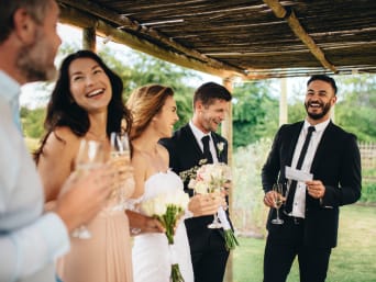Juegos de boda: los novios de una boda y un grupo de invitados ríen juntos.