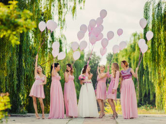 Outfit voor vrouwelijke bruiloftsgasten: bruid & bruidsmeisjes in roze jurken laten ballonnen opstijgen.