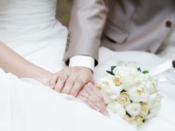 Huwelijk: bruid en bruidegom houden elkaars handen vast.