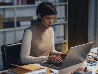 Jak się ubrać do pracy w domu – kobieta w stylowym stroju pracuje na komputerze.