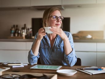Work-life-balance in smart working: una donna si rilassa durante una pausa caffè.
