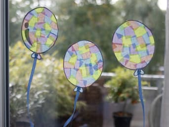 Ozdoby karnawałowe z bibuły – witraże w kształcie kolorowych balonów na oknie.