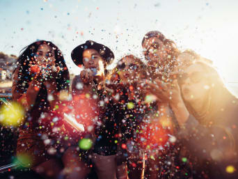 Karnawał – tradycje i zwyczaje, grupa przyjaciół sypie konfetti.