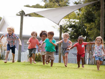 Éducation petite enfance : des bambins font un jeux de mouvement à l’extérieur.