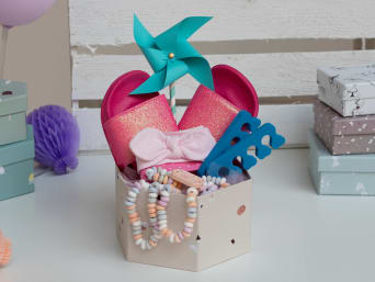 Regali di compleanno per bambine: un piccolo Beauty-Set con una fascia per capelli, una collana di caramelle e dei sandali glitterati.