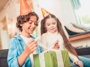 Kindercadeau vanaf 6 jaar: jongen opent zijn verjaardagscadeau met zijn zus.
