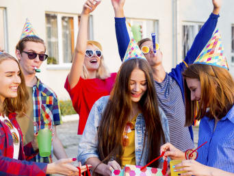 Oryginalne prezenty dla nastolatków – młodzież podczas imprezy urodzinowej otwiera upominki.