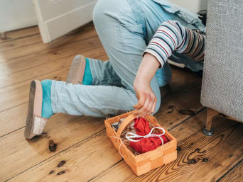 Ostergeschenke Kinder: Kind schaut unter dem Sofa nach einem Ostergeschenk.