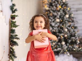 Christmas gifts for girls – a young girl holding her Christmas present.