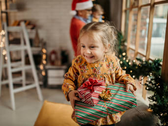 Cadeaux de Noël pour enfants : une petite fille de 2 ans porte ses cadeaux de Noël.