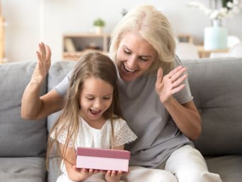 Gifts for children aged 2 and over. A granddaughter opens a present from her grandmother.