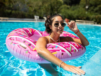 Idée cadeau ado fille de 17 ans : une adolescente se détend avec une bouée gonflable dans une piscine.