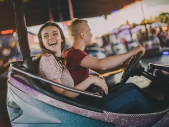 Ideas de regalos para adolescentes: dos jóvenes se divierten en los coches de choque en un parque de atracciones.