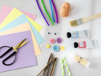 Bastelideen für den Kindertag: Benötigte Bastelmaterialien wie Karton, Knöpfe und Farben sind von oben zu sehen.