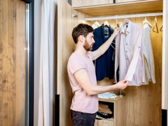 Come riordinare l’armadio: un uomo dà un’occhiata alle camicie nell’armadio.