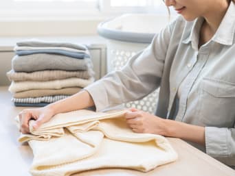 Come piegare maglioni: una donna piega una pila di maglioncini.