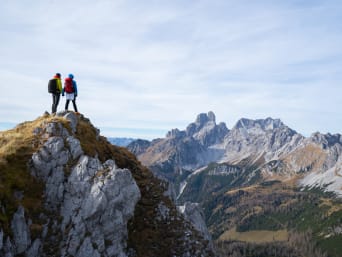 Dos aficionados a los deportes de montaña contemplan las vistas desde lo alto de una cima.