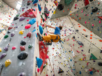Un hombre escala una pared de una sala de escalada.