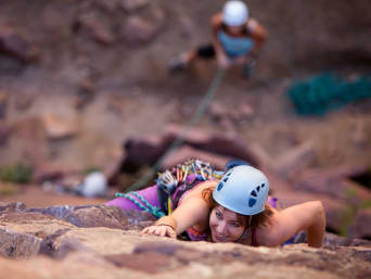 Arrampicata in montagna – Una ragazza scala con il casco per proteggere la testa