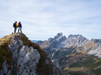 Beneficios del alpinismo: dos alpinistas observan las vistas desde lo alto de una montaña.