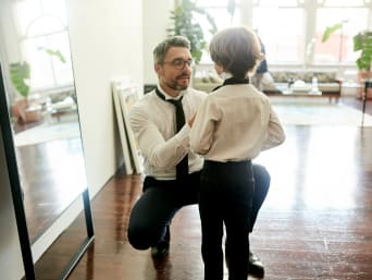 Strój komunijny dla chłopca: tata pomaga synowi zawiązać krawat.
