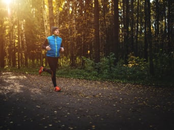 Laufen im Herbst: Mann joggt auf einem Waldweg.