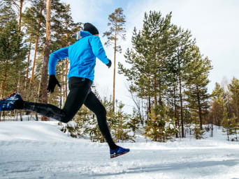 Going for a run in winter: a man running on a snow covered track.