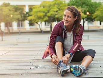 Blijf gezond door te joggen - vrouw strikt de veters van haar hardloopschoenen.